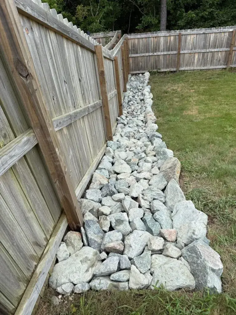 Rock drainage solution along fence line